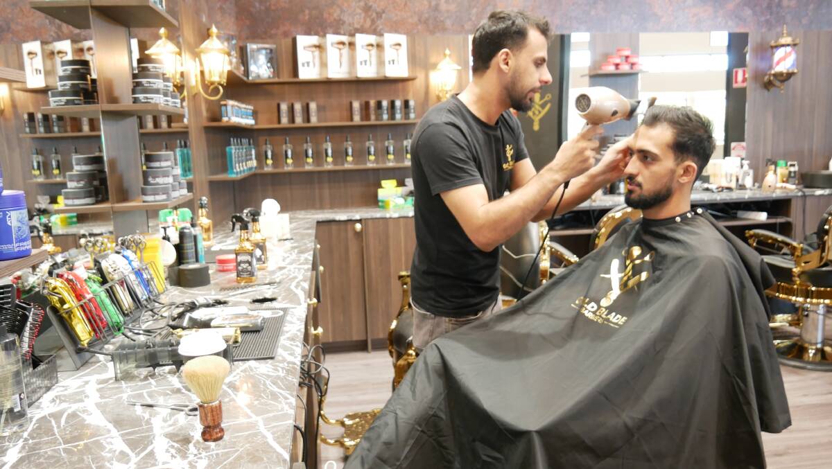 Ammar Jashami (seated) has recently opened a Gold Blade Barber shop inside Sapphire Marketplace in Bega with great success. Photo: Ellouise Bailey 