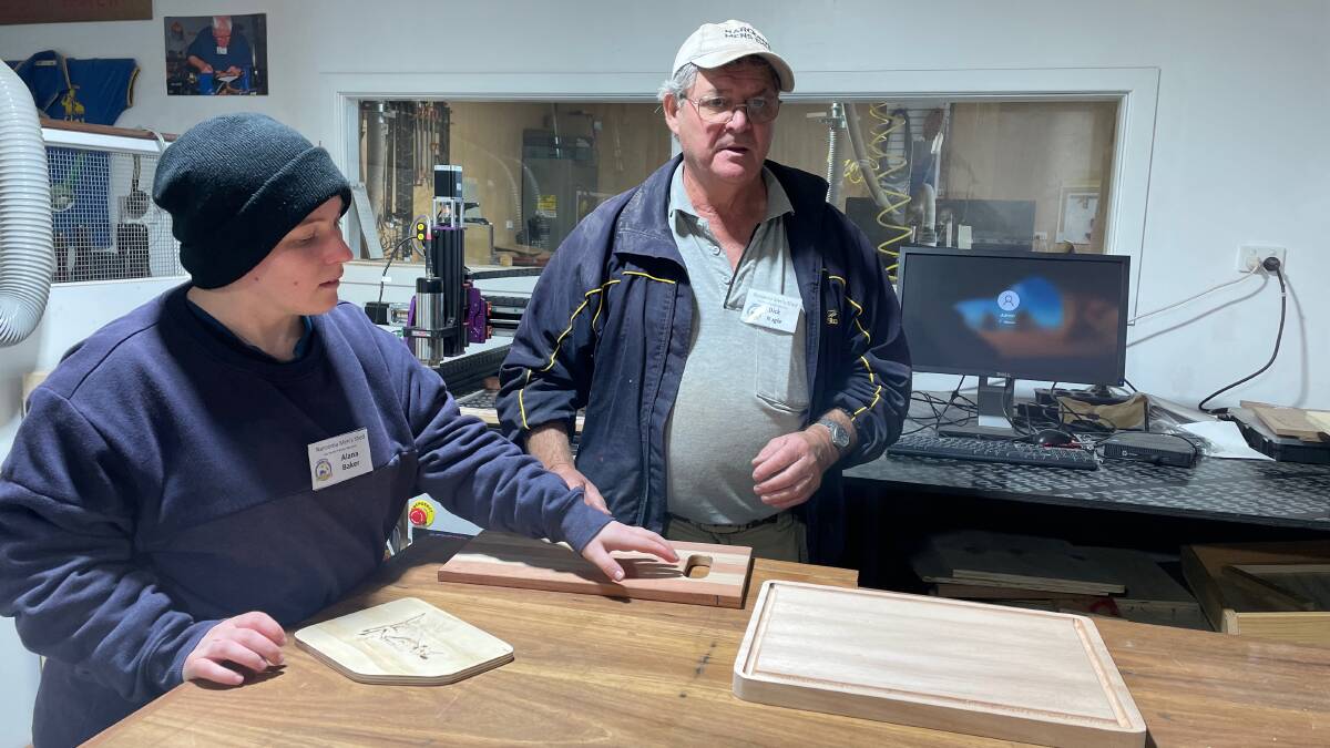 Woodworking instructor Dick Nagel is about to teach Alana Baker how to add a juice groove to the cutting board she made at the Narooma Community Men's Shed Woodworking for Mental Health classes. The shed has a great range of machinery. Picture by Marion Williams