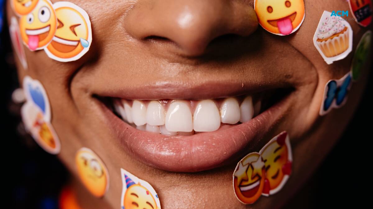 A smiling face dotted with emoji stickers. Picture via Canva