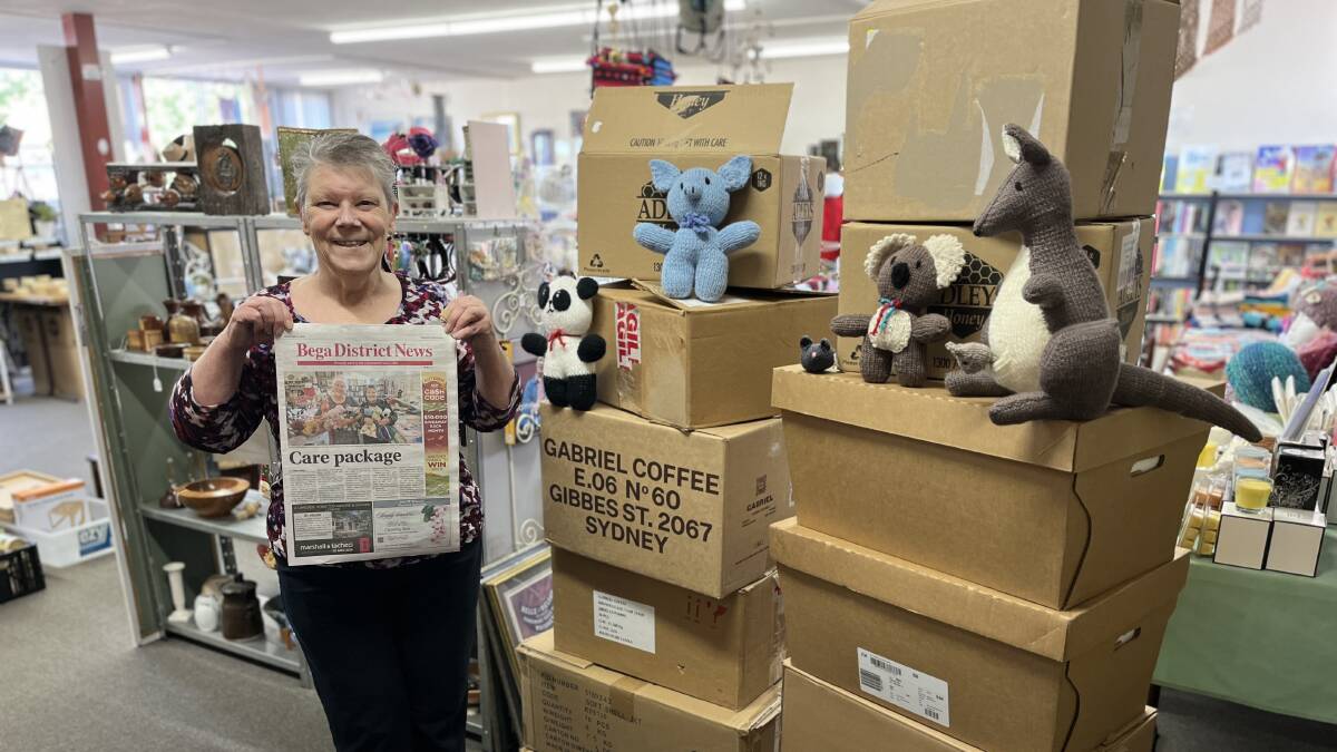 Owner of Bega Valley Market Place, Pam Burgess holding the original Bega District News article while standing alongside just a handful of care packages to be sent to Kyiv. Picture by James Parker