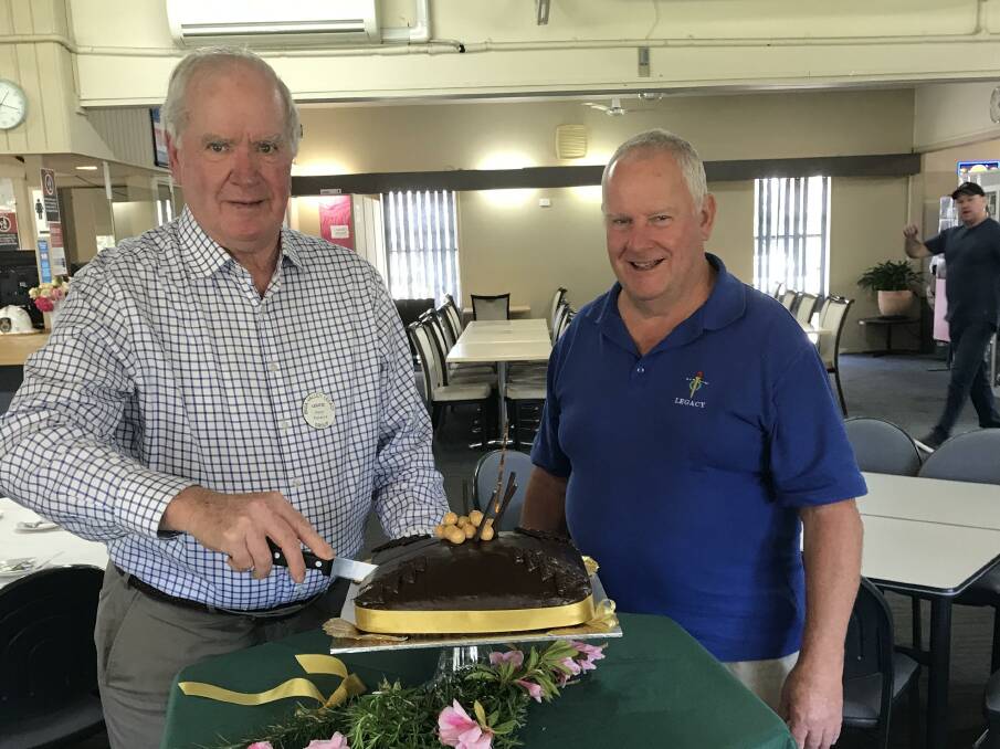 Peter Florance from the Wollongong Legacy and South Coast is cutting the cake while local legatee Rex Kermode is looking on. Picture supplied.