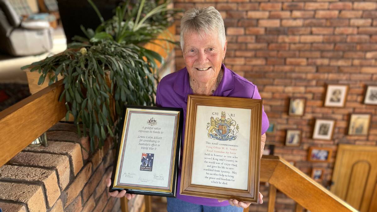 Wendy Elliott holding two frames that commemorate the services of her late husband and her late father. Picture by James Parker.